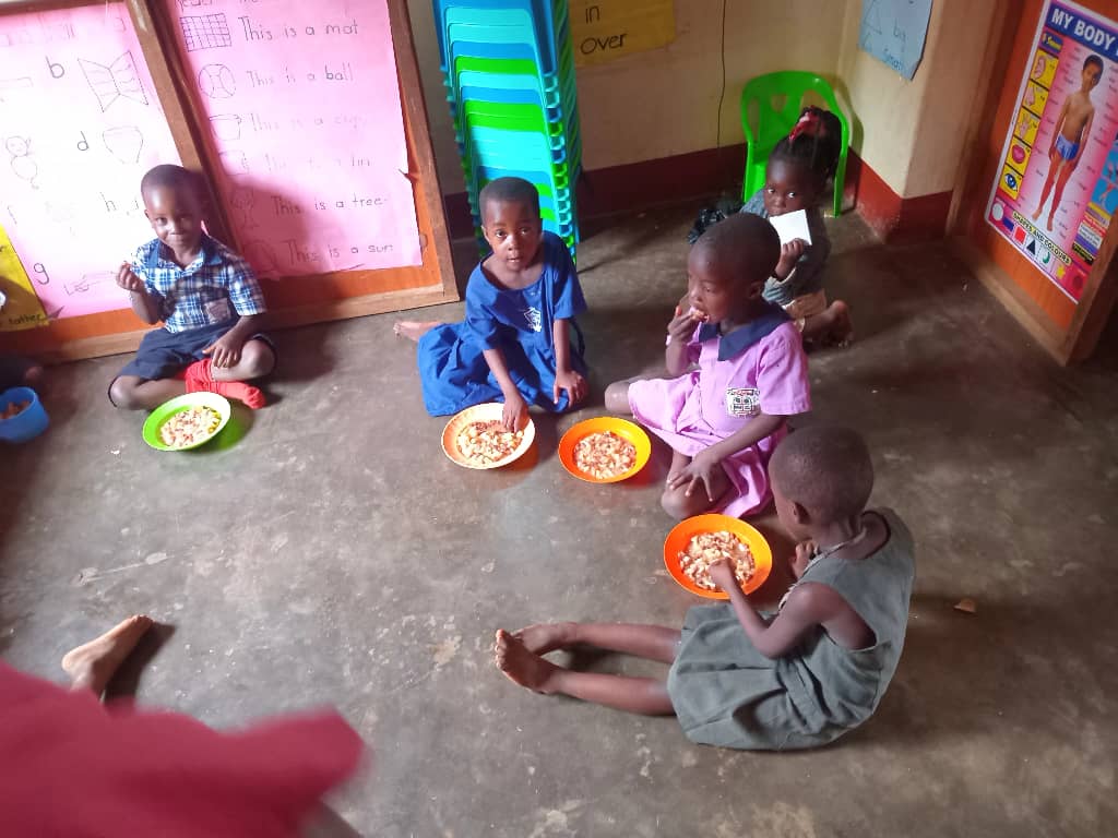 Children eating a healthy meal in the classroom at Hope Caring CBO