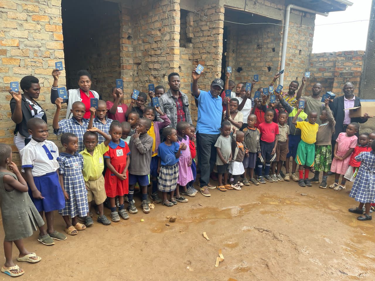 Hope Caring CBO children and staff holding books together in Uganda