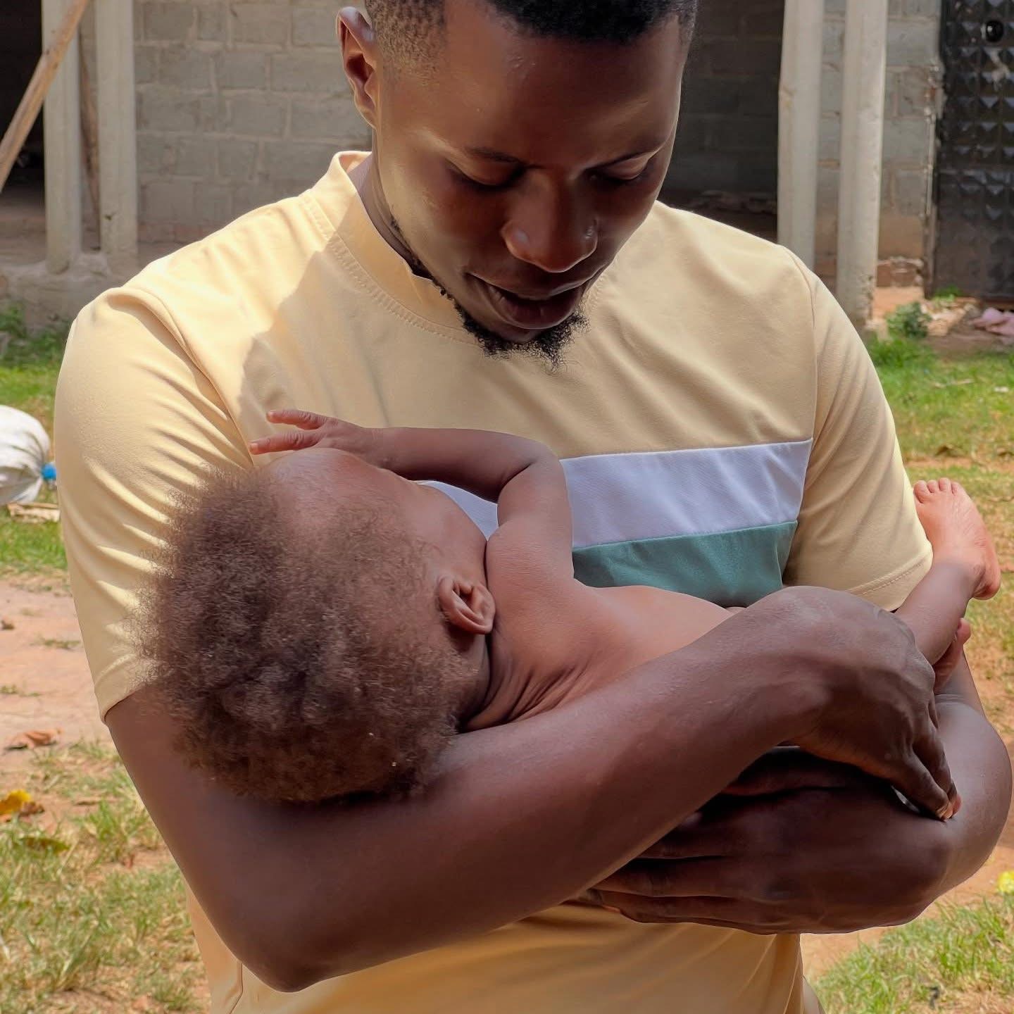 Co-founder Ssozi Zadimiina gently holding an infant in care