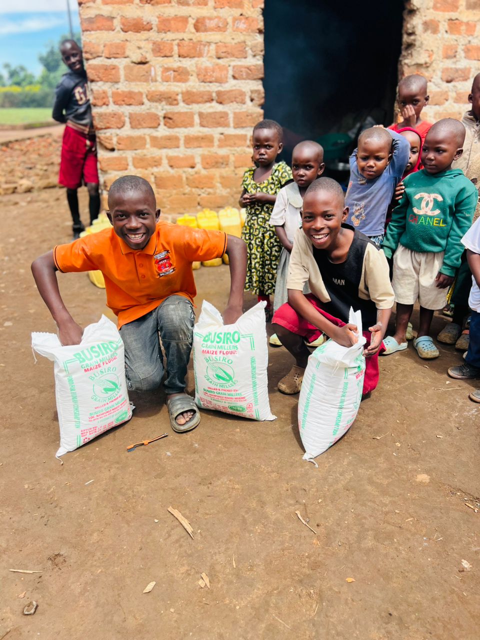 Children proudly holding bags of maize flour food donations